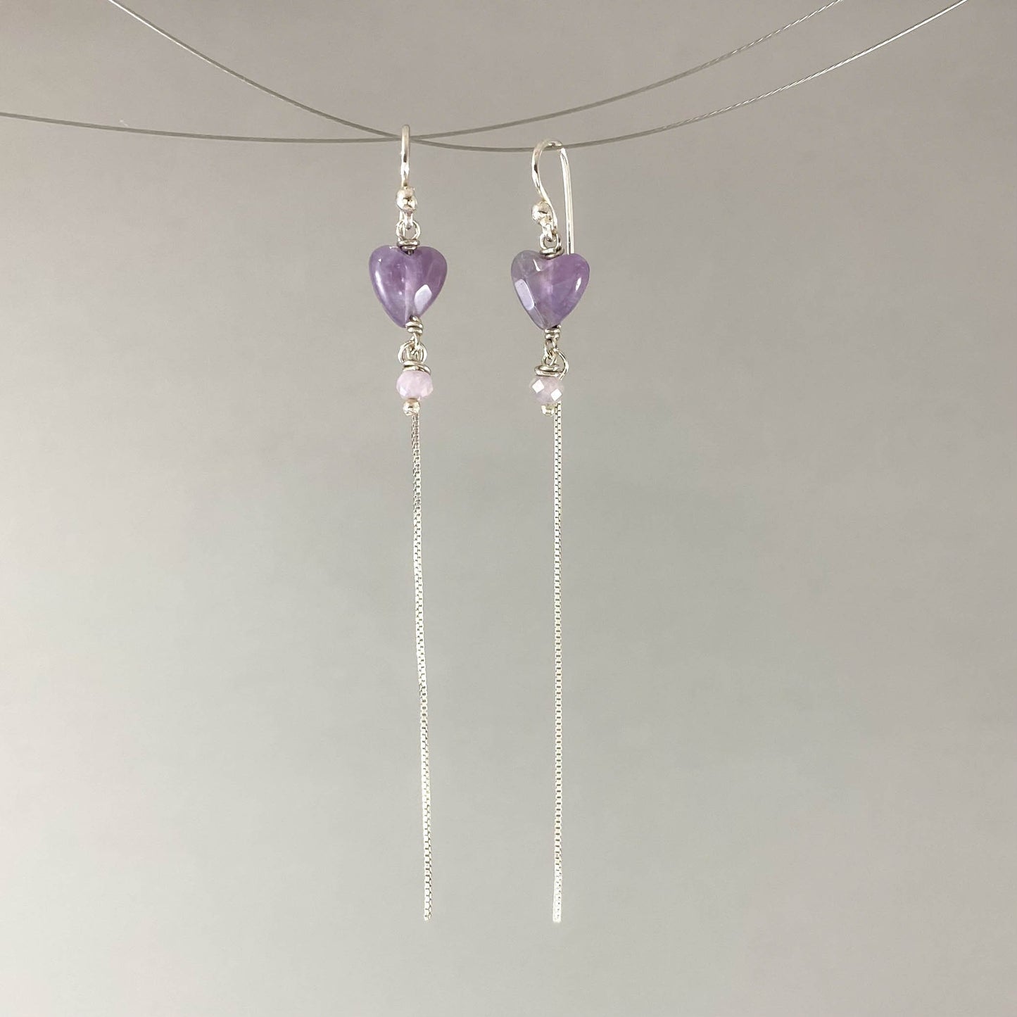 Brinco com gancho anzol, pedras coração ametista. Corrente veneziana 925 polida (clara) 6cm. Embalagem em envelope de tecido, com cartão postal Amor Maior. Esta é uma joia de prata 925 produzida com uma liga conhecida internacionalmente com STERLING SILVER – 925, o que significa que ela é constituída de 92,5% de prata pura, garantindo a qualidade do material utilizado. Por se tratar de pedras naturais, podem apresentar variações na coloração.