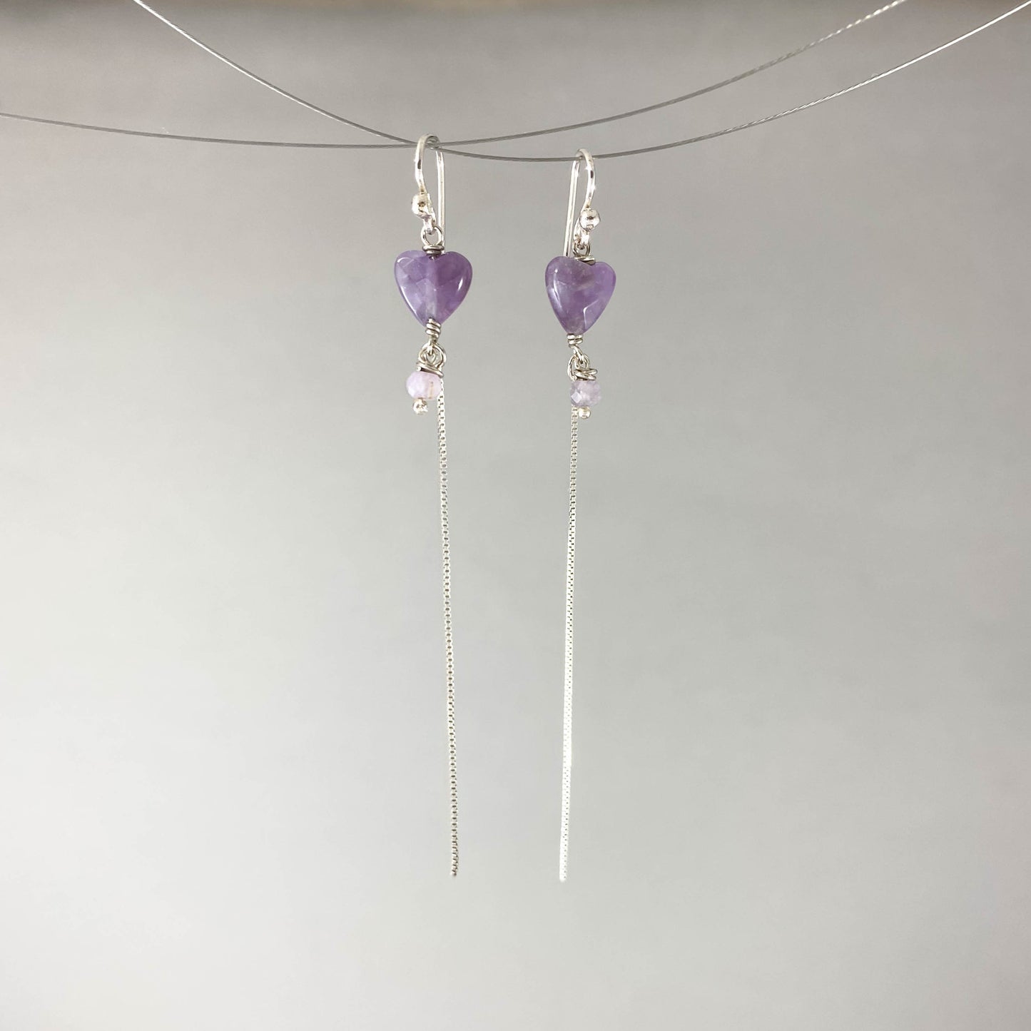 Brinco com gancho anzol, pedras coração ametista. Corrente veneziana 925 polida (clara) 6cm. Embalagem em envelope de tecido, com cartão postal Amor Maior. Esta é uma joia de prata 925 produzida com uma liga conhecida internacionalmente com STERLING SILVER – 925, o que significa que ela é constituída de 92,5% de prata pura, garantindo a qualidade do material utilizado. Por se tratar de pedras naturais, podem apresentar variações na coloração.