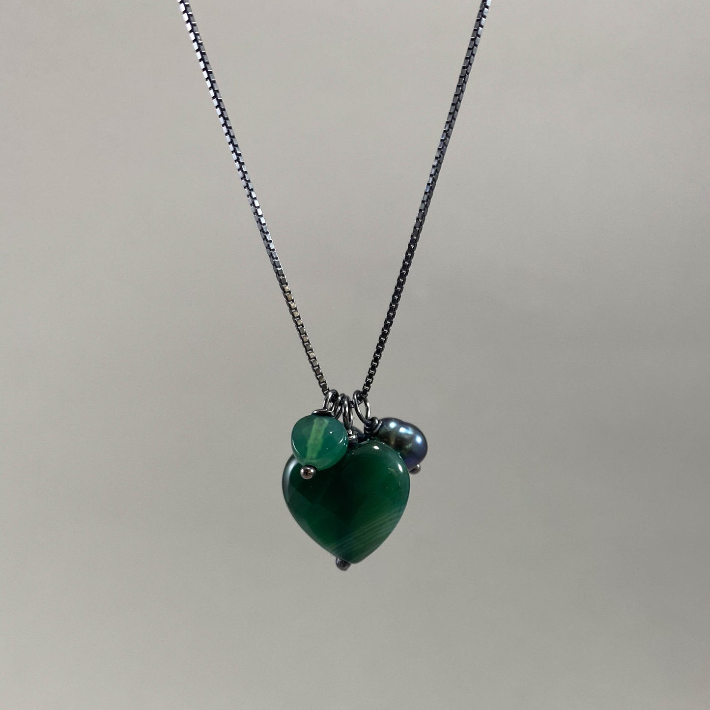 Colar corrente veneziana prata 925 oxidada (escura), com pingentes em pedras ágata verde e pérola negra. Comprimento: 70cm. Embalagem em envelope de tecido, com cartão postal Amor Maior. Esta é uma joia de prata 925 produzida com uma liga conhecida internacionalmente com STERLING SILVER – 925, o que significa que ela é constituída de 92,5% de prata pura, garantindo a qualidade do material utilizado. Por se tratar de pedras naturais, podem apresentar variações na coloração.