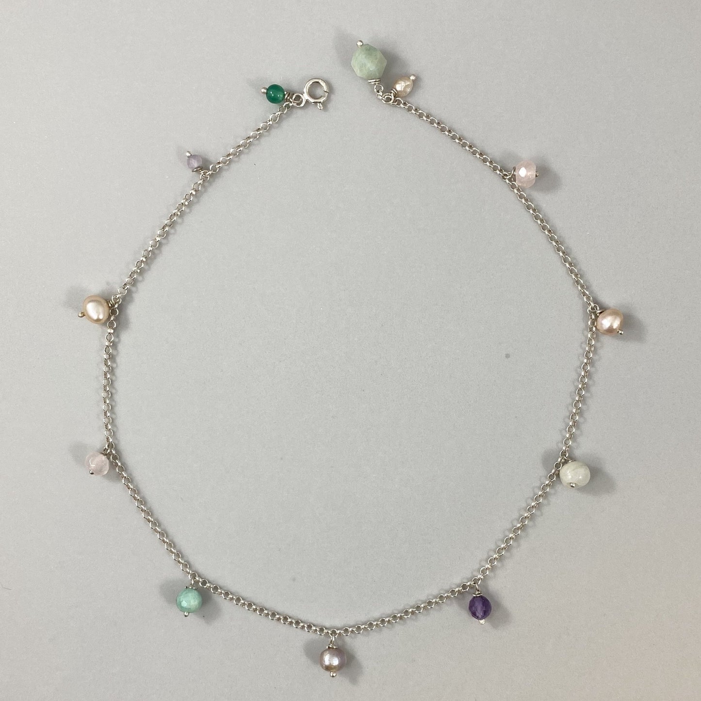 Colar em corrente elo português em prata 925 polida (clara), com pedras amazonita, quartzo rosa, pérola, ametista e ágata verde. Comprimento: 39 cm. Embalagem de algodão Santacosta. Esta é uma joia de prata 925 produzida com uma liga conhecida internacionalmente com STERLING SILVER – 925, o que significa que ela é constituída de 92,5% de prata pura, garantindo a qualidade do material utilizado. Por se tratar de pedras naturais, podem apresentar variações na coloração.