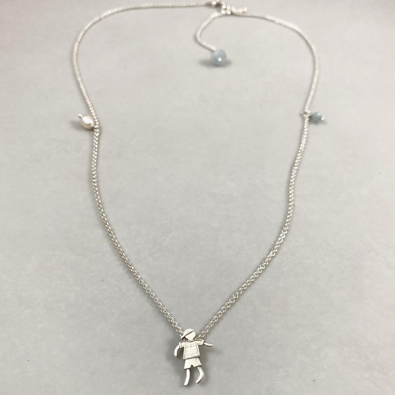 Colar corrente elo português mini prata 925 polida (clara), com pingente menino 14mm e detalhes em pérolas naturais e água marinha. Comprimento em três regulagens: 35cm, 45cm e 50cm. Embalagem em envelope de tecido, com cartão postal Amor Maior. Esta é uma joia de prata 925 produzida com uma liga conhecida internacionalmente com STERLING SILVER – 925, o que significa que ela é constituída de 92,5% de prata pura, garantindo a qualidade do material utilizado. Por se tratar de pedras naturais, podem apresentar