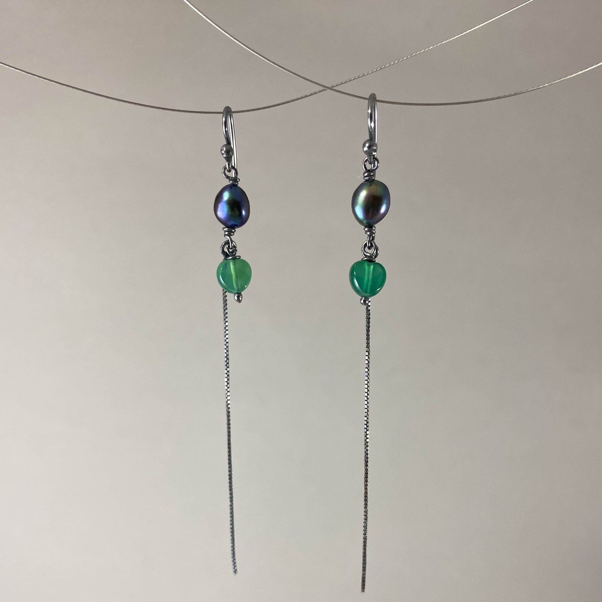 Brinco com gancho anzol, pedra ágata verde e pérola negra. Corrente veneziana 925 oxidada (escura) 6 cm. Embalagem em envelope de tecido, com cartão postal Amor Maior. Esta é uma joia de prata 925 produzida com uma liga conhecida internacionalmente com STERLING SILVER – 925, o que significa que ela é constituída de 92,5% de prata pura, garantindo a qualidade do material utilizado. Por se tratar de pedras naturais, podem apresentar variações na coloração.