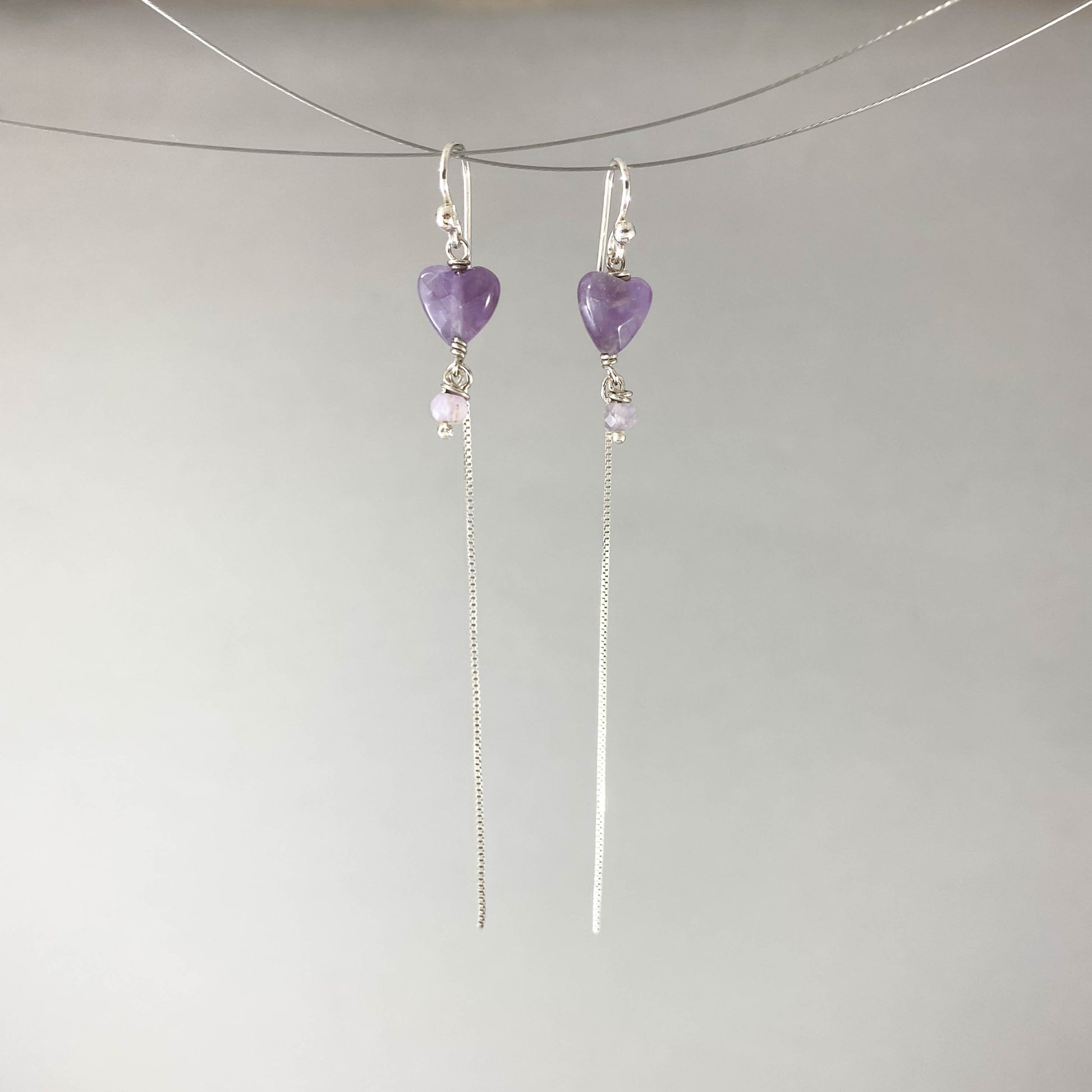 Brinco com gancho anzol, pedras coração ametista. Corrente veneziana 925 polida (clara) 6cm. Embalagem em envelope de tecido, com cartão postal Amor Maior. Esta é uma joia de prata 925 produzida com uma liga conhecida internacionalmente com STERLING SILVER – 925, o que significa que ela é constituída de 92,5% de prata pura, garantindo a qualidade do material utilizado. Por se tratar de pedras naturais, podem apresentar variações na coloração.