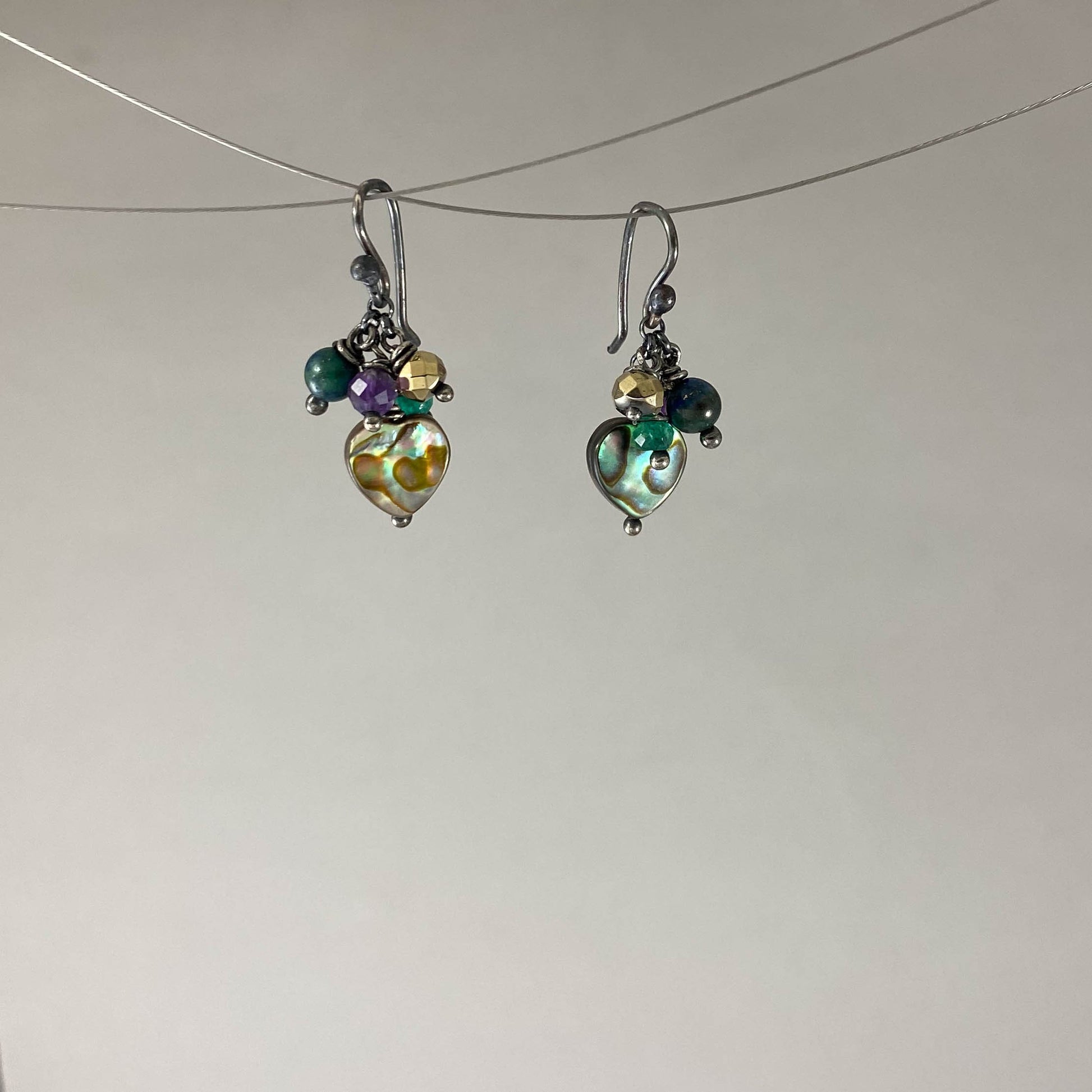 Brinco com gancho anzol, pedras abalone, ágata verde, ametista, crisocola e hematita dourada. Embalagem em envelope de tecido, com cartão postal Amor Maior. Esta é uma joia de prata 925 produzida com uma liga conhecida internacionalmente com STERLING SILVER – 925, o que significa que ela é constituída de 92,5% de prata pura, garantindo a qualidade do material utilizado. Por se tratar de pedras naturais, podem apresentar variações na coloração.