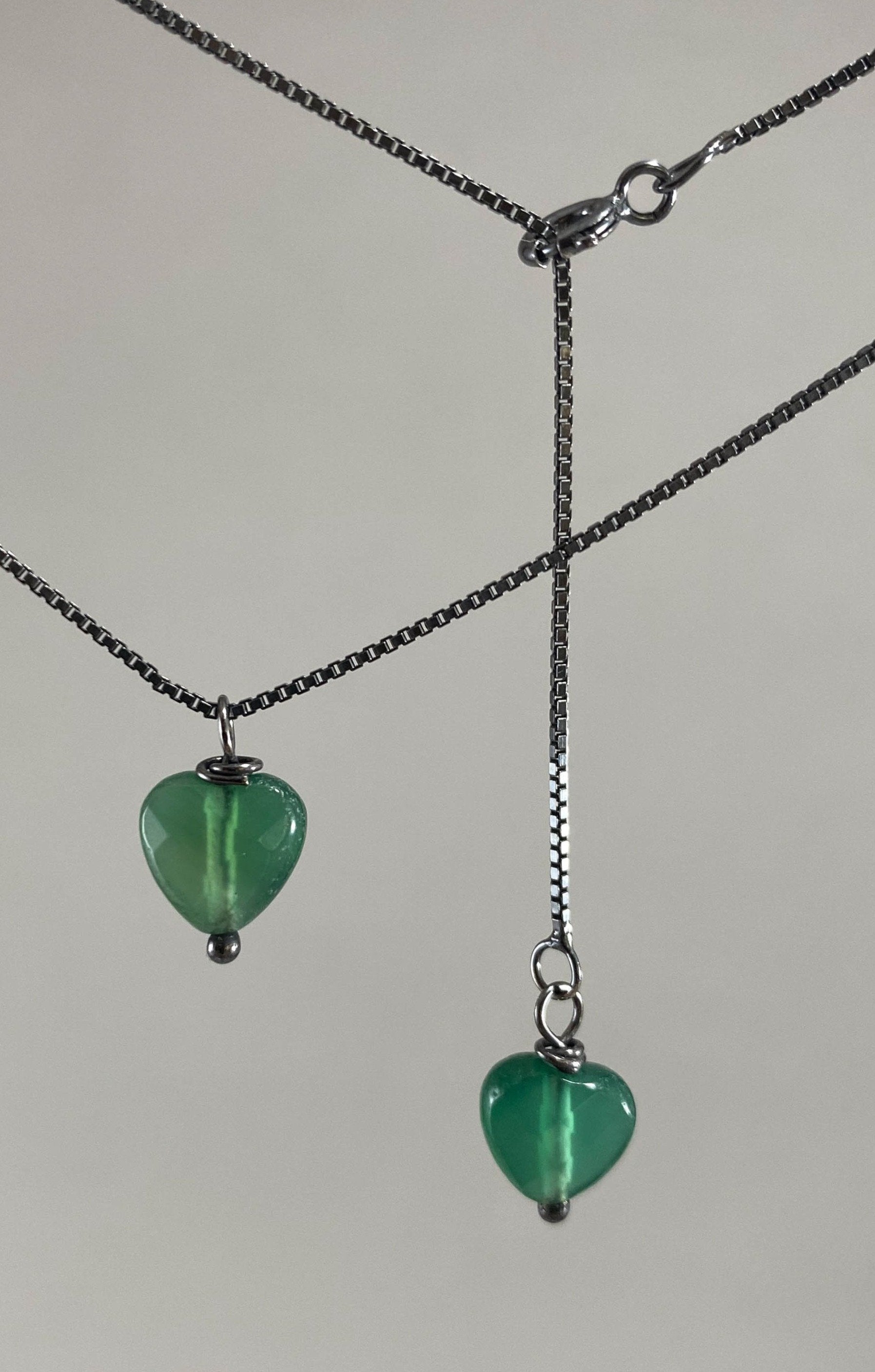 Colar corrente veneziana prata 925 oxidada (escura), com pingentes em pedras coração ágata verde. Comprimento: 45cm. Embalagem em envelope de tecido, com cartão postal Amor Maior. Esta é uma joia de prata 925 produzida com uma liga conhecida internacionalmente com STERLING SILVER – 925, o que significa que ela é constituída de 92,5% de prata pura, garantindo a qualidade do material utilizado. Por se tratar de pedras naturais, podem apresentar variações na coloração.