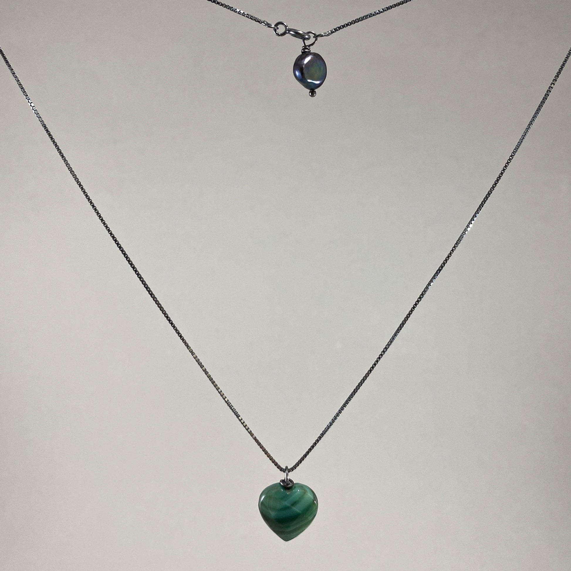 Colar corrente veneziana prata 925 oxidada (escura), com pingentes em pedras coração ágata verde e pérola negra. Comprimento: 50cm. Embalagem em envelope de tecido, com cartão postal Amor Maior. Esta é uma joia de prata 925 produzida com uma liga conhecida internacionalmente com STERLING SILVER – 925, o que significa que ela é constituída de 92,5% de prata pura, garantindo a qualidade do material utilizado. Por se tratar de pedras naturais, podem apresentar variações na coloração.