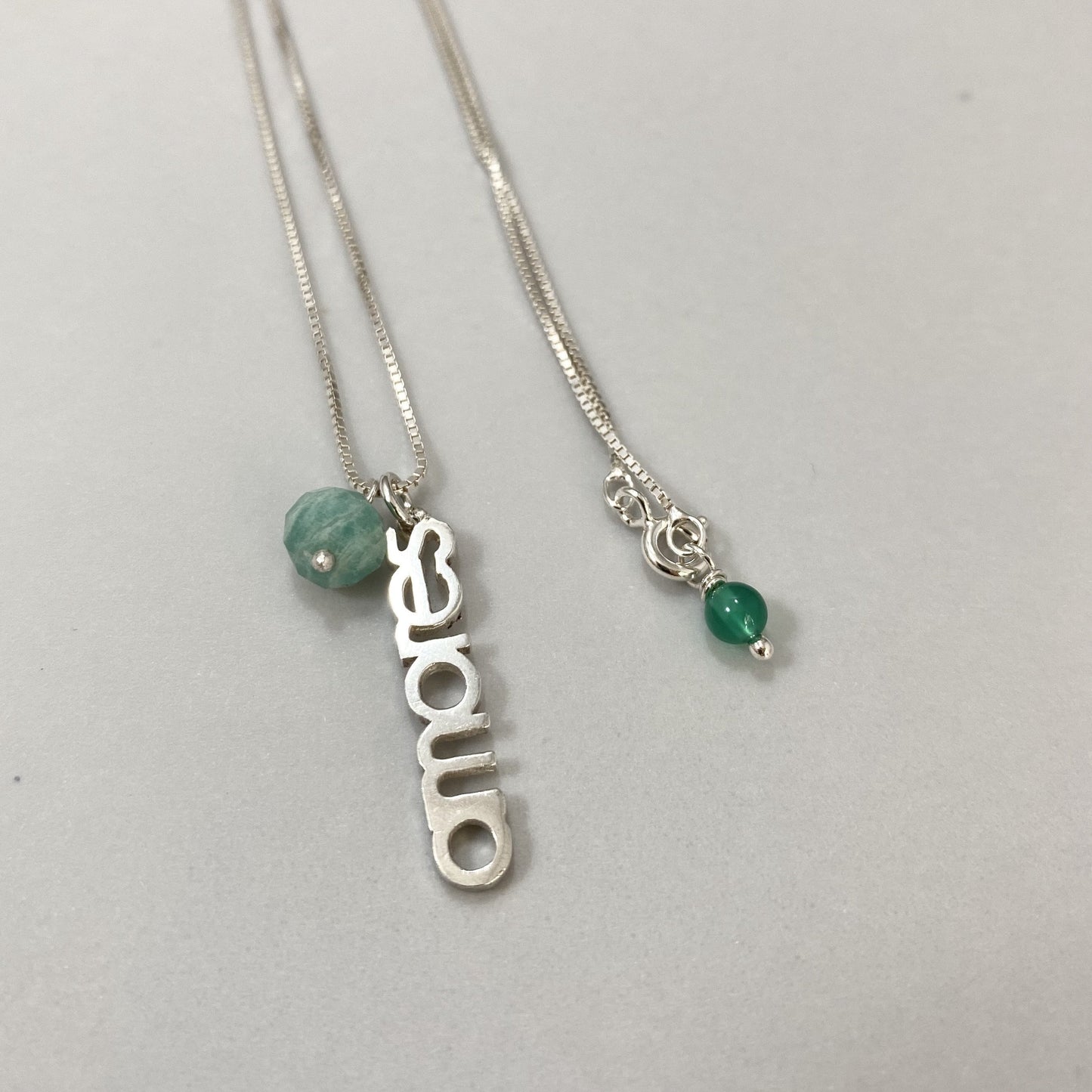 Colar em corrente veneziana e pingente amores em prata 925 polida (clara), com pedras amazonita e ágata verde. Comprimento: 45 cm. Embalagem de algodão Santacosta. Esta é uma joia de prata 925 produzida com uma liga conhecida internacionalmente com STERLING SILVER – 925, o que significa que ela é constituída de 92,5% de prata pura, garantindo a qualidade do material utilizado. Por se tratar de pedras naturais, podem apresentar variações na coloração.