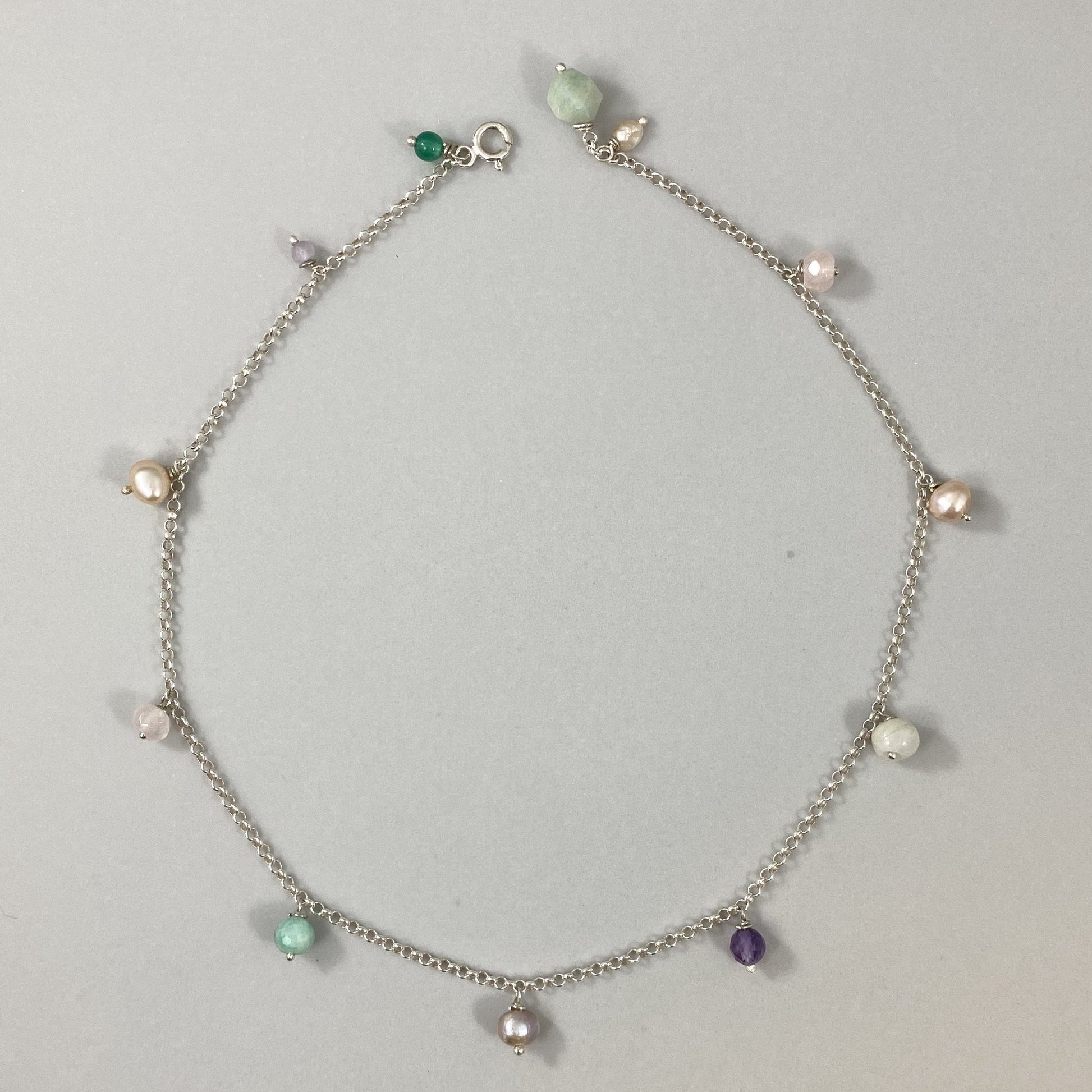 Colar em corrente elo português em prata 925 polida (clara), com pedras amazonita, quartzo rosa, pérola, ametista e ágata verde. Comprimento: 39 cm. Embalagem de algodão Santacosta. Esta é uma joia de prata 925 produzida com uma liga conhecida internacionalmente com STERLING SILVER – 925, o que significa que ela é constituída de 92,5% de prata pura, garantindo a qualidade do material utilizado. Por se tratar de pedras naturais, podem apresentar variações na coloração.