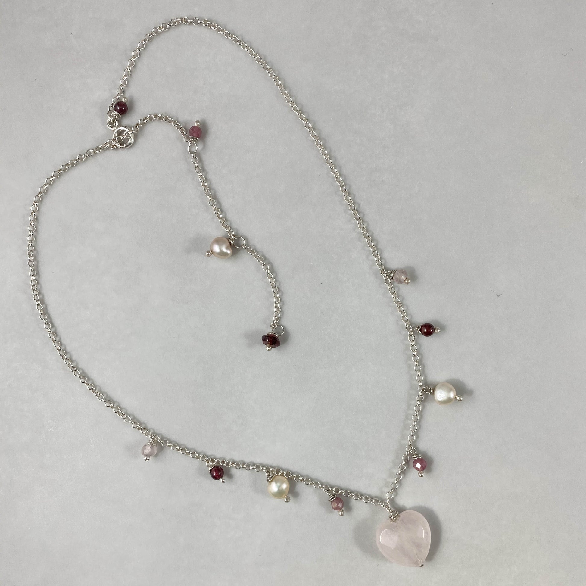 Colar corrente elo português aberto prata 925 polida (clara), com pingentes em pedras coração quartzo rosa, turmalina, pérola rosa e granada. Comprimento: 45cm. Embalagem em envelope de tecido, com cartão postal Amor Maior. Esta é uma joia de prata 925 produzida com uma liga conhecida internacionalmente com STERLING SILVER – 925, o que significa que ela é constituída de 92,5% de prata pura, garantindo a qualidade do material utilizado. Por se tratar de pedras naturais, podem apresentar variações na coloraçã