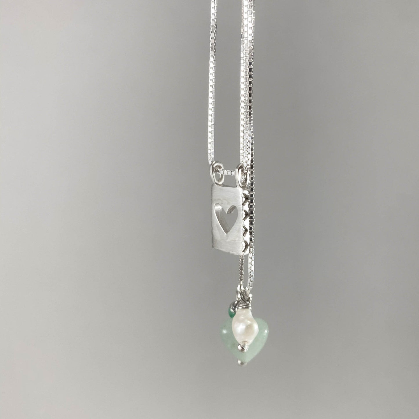 Colar corrente veneziana prata 925 polida (clara) com pingentes em pedras coração quartzo verde, pérola branca e placa coração vazado em prata 925 polida (clara). Comprimento: 70cm. Embalagem em envelope de tecido, com cartão postal Amor Maior. Esta é uma joia de prata 925 produzida com uma liga conhecida internacionalmente com STERLING SILVER – 925, o que significa que ela é constituída de 92,5% de prata pura, garantindo a qualidade do material utilizado. Por se tratar de pedras naturais, podem apresentar 