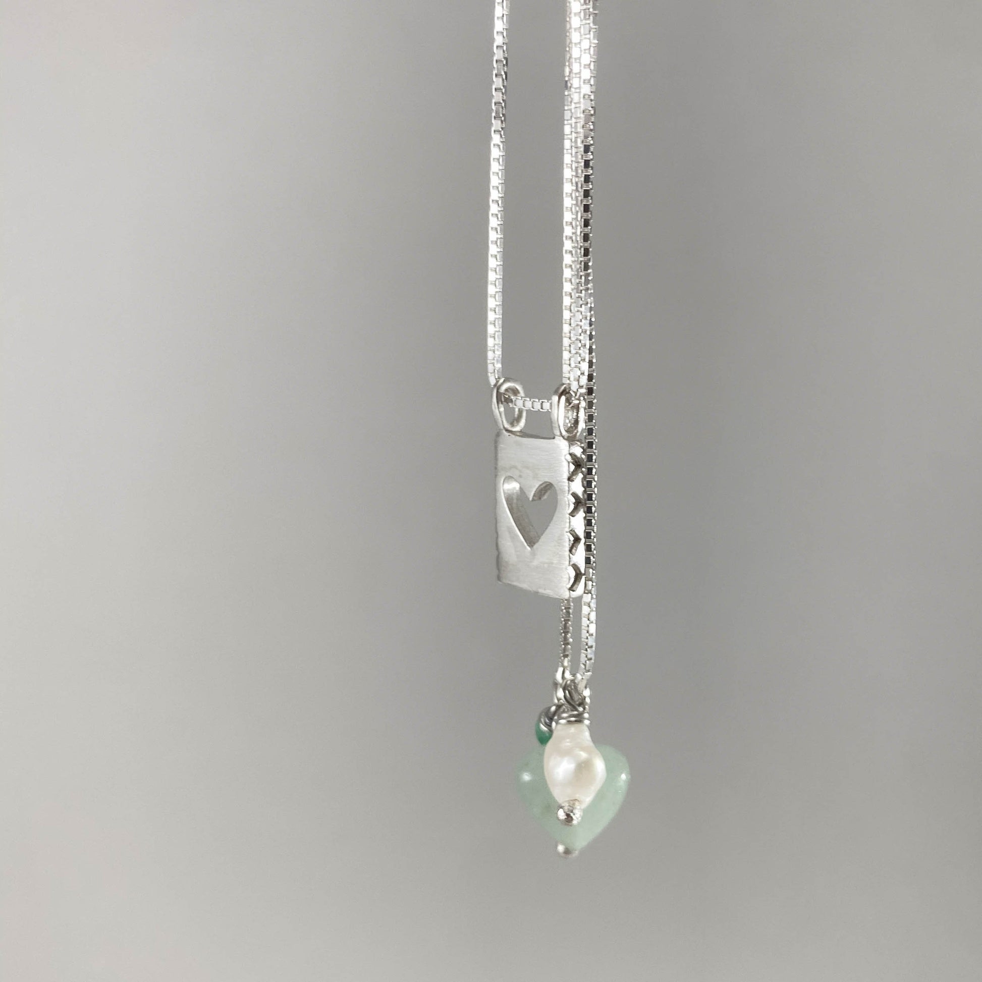 Colar corrente veneziana prata 925 polida (clara) com pingentes em pedras coração quartzo verde, pérola branca e placa coração vazado em prata 925 polida (clara). Comprimento: 70cm. Embalagem em envelope de tecido, com cartão postal Amor Maior. Esta é uma joia de prata 925 produzida com uma liga conhecida internacionalmente com STERLING SILVER – 925, o que significa que ela é constituída de 92,5% de prata pura, garantindo a qualidade do material utilizado. Por se tratar de pedras naturais, podem apresentar 