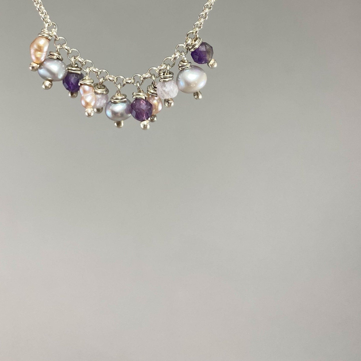 Pulseira corrente elo português em prata 925 polida (clara), com pedras ametista lavanda, pérolas e ametista. Comprimento: regulagem entre 15cm e 18cm. Para outras medidas entre em contato. Embalagem em envelope de tecido, com cartão postal Amor Maior. Esta é uma joia de prata 925 produzida com uma liga conhecida internacionalmente com STERLING SILVER – 925, o que significa que ela é constituída de 92,5% de prata pura, garantindo a qualidade do material utilizado. Por se tratar de pedras naturais, podem apr