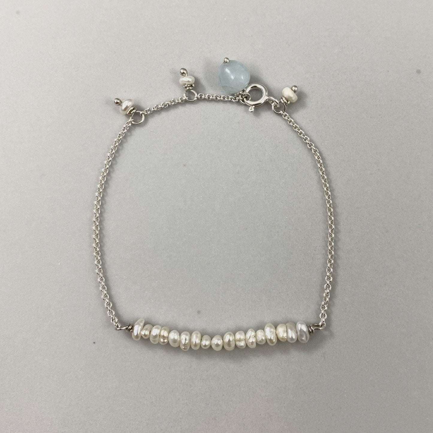 Pulseira corrente cartier em prata 925 polida (clara), com pedras pérola com água-marinha. Comprimento: regulagem entre 15cm e 18cm. Para outras medidas entre em contato. Embalagem de algodão Santacosta. Esta é uma joia de prata 925 produzida com uma liga conhecida internacionalmente com STERLING SILVER – 925, o que significa que ela é constituída de 92,5% de prata pura, garantindo a qualidade do material utilizado. Por se tratar de pedras naturais, podem apresentar variações na coloração.