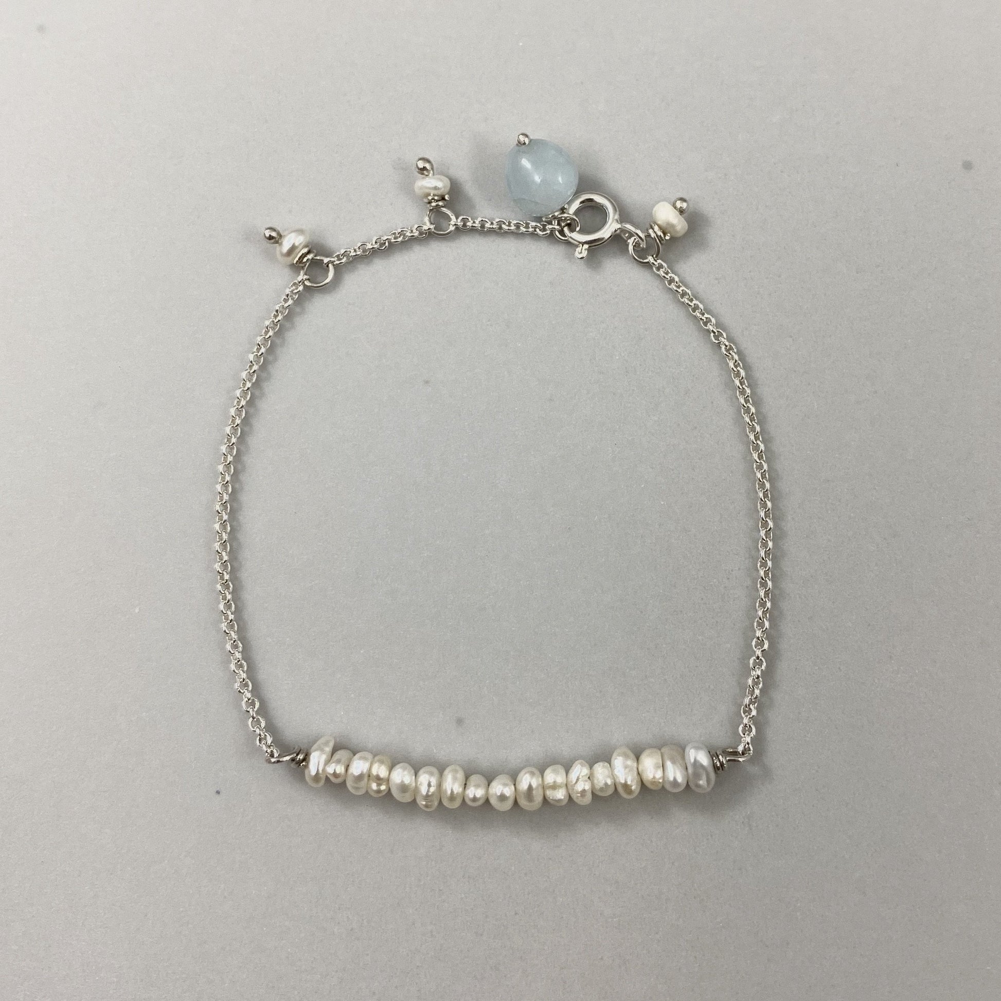 Pulseira corrente cartier em prata 925 polida (clara), com pedras pérola com água-marinha. Comprimento: regulagem entre 15cm e 18cm. Para outras medidas entre em contato. Embalagem de algodão Santacosta. Esta é uma joia de prata 925 produzida com uma liga conhecida internacionalmente com STERLING SILVER – 925, o que significa que ela é constituída de 92,5% de prata pura, garantindo a qualidade do material utilizado. Por se tratar de pedras naturais, podem apresentar variações na coloração.