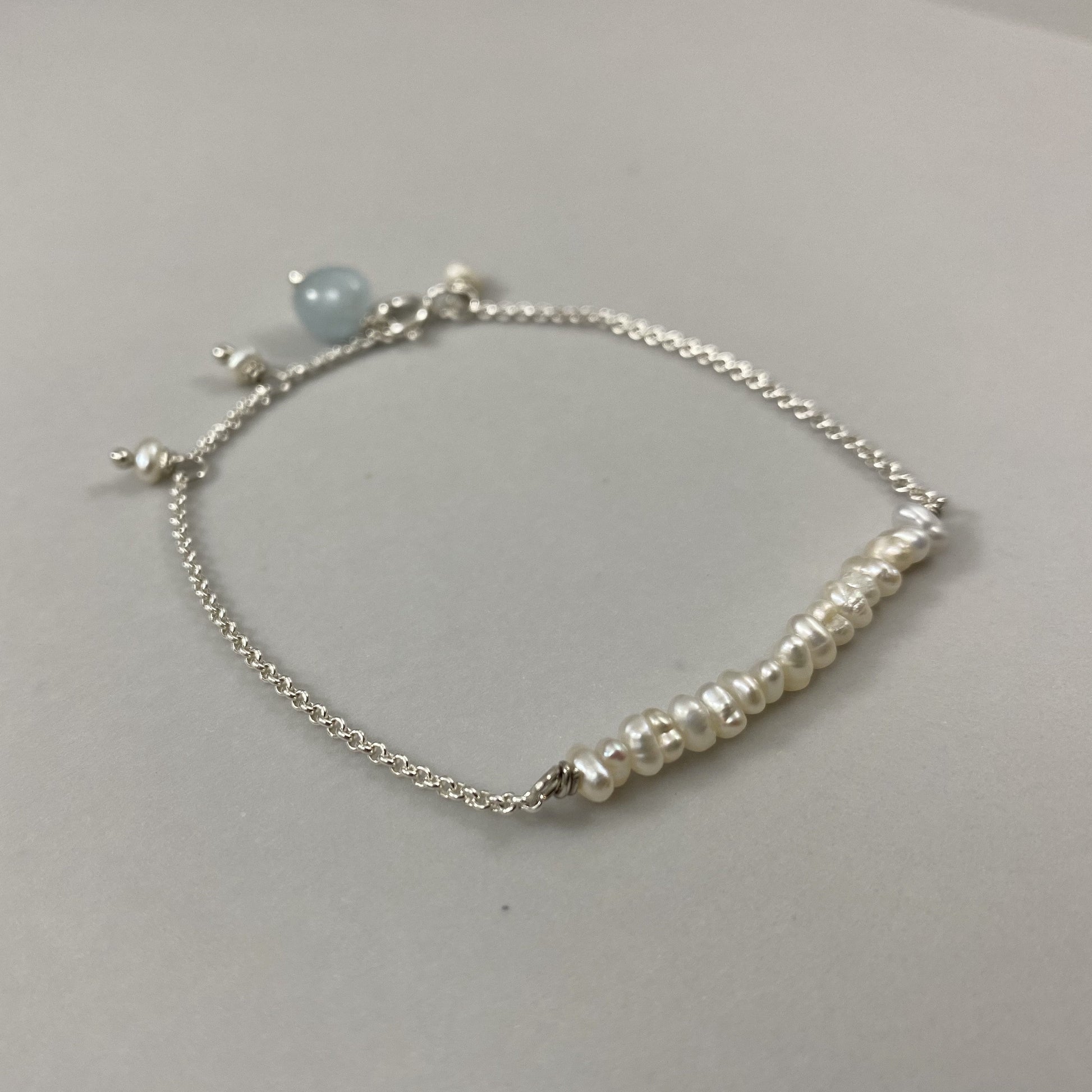 Pulseira corrente cartier em prata 925 polida (clara), com pedras pérola com água-marinha. Comprimento: regulagem entre 15cm e 18cm. Para outras medidas entre em contato. Embalagem de algodão Santacosta. Esta é uma joia de prata 925 produzida com uma liga conhecida internacionalmente com STERLING SILVER – 925, o que significa que ela é constituída de 92,5% de prata pura, garantindo a qualidade do material utilizado. Por se tratar de pedras naturais, podem apresentar variações na coloração.