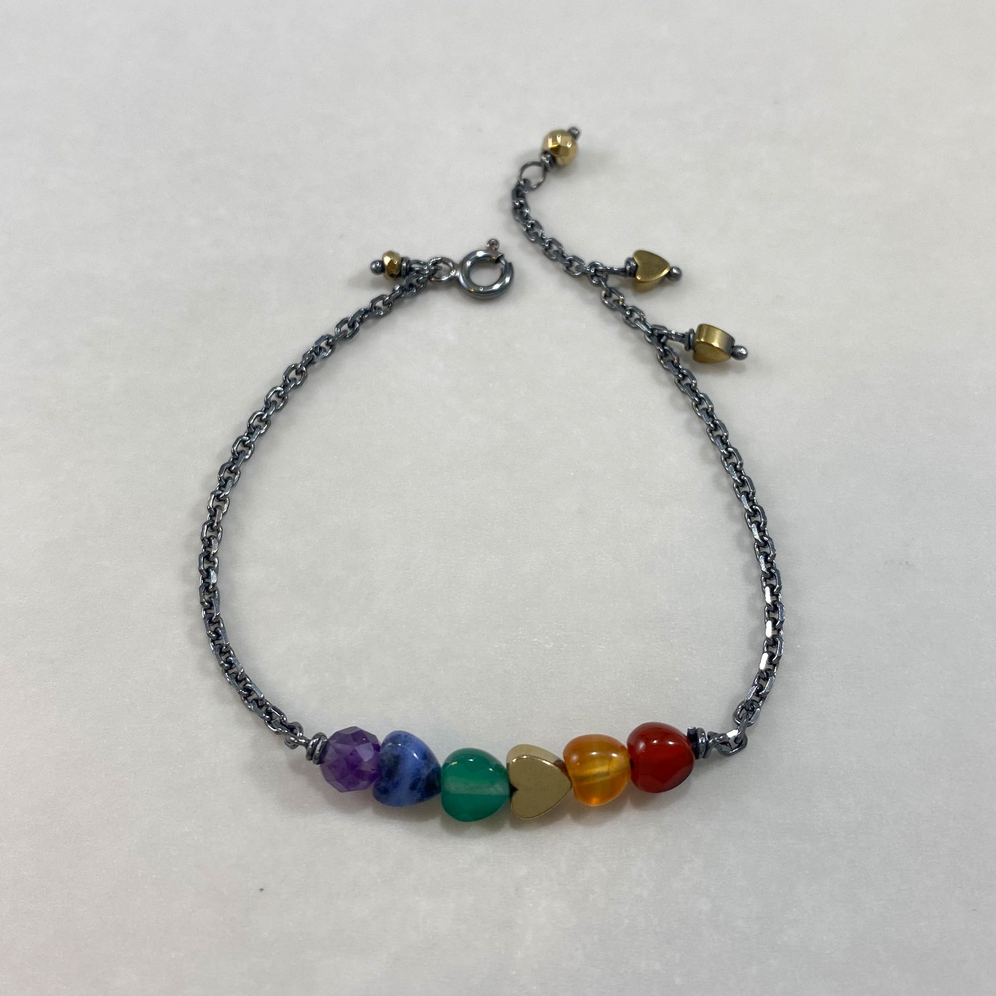 Pulseira corrente cartier prata 925 oxidada (escura), com pedras hematita dourada, ametista, sodalita, ágata verde e ágata cornalina. Comprimento: regulagem entre 15cm e 18cm. Para outras medidas entre em contato. Embalagem em envelope de tecido, com cartão postal Amor Maior. Esta é uma joia de prata 925 produzida com uma liga conhecida internacionalmente com STERLING SILVER – 925, o que significa que ela é constituída de 92,5% de prata pura, garantindo a qualidade do material utilizado. Por se tratar de pe