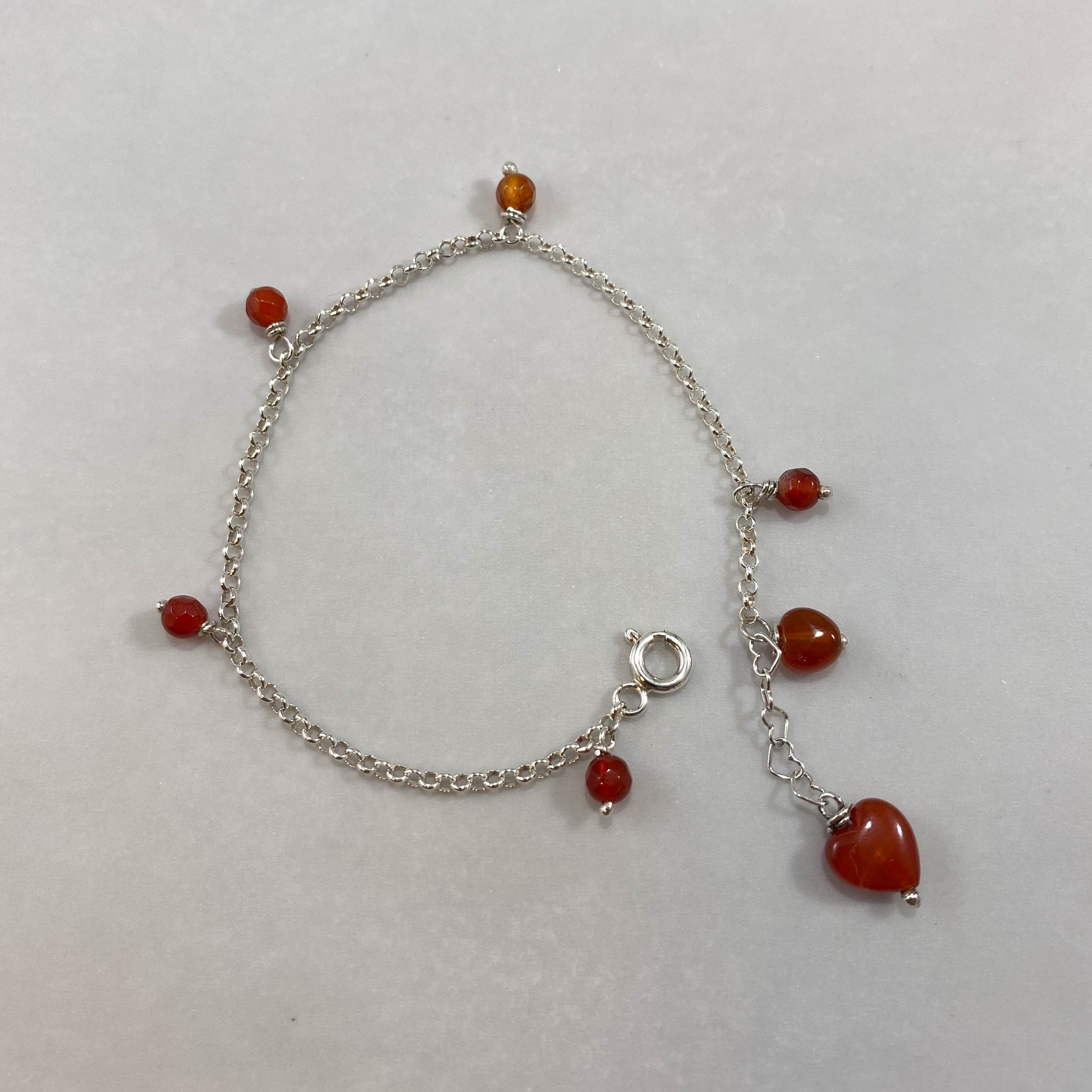 Pulseira corrente elo português prata 925 polida (clara), com pingentes em pedras ágata cornalina. Comprimento: regulagem entre 15cm e 18cm. Para outras medidas entre em contato. Embalagem em envelope de tecido, com cartão postal Amor Maior. Esta é uma joia de prata 925 produzida com uma liga conhecida internacionalmente com STERLING SILVER – 925, o que significa que ela é constituída de 92,5% de prata pura, garantindo a qualidade do material utilizado. Por se tratar de pedras naturais, podem apresentar var
