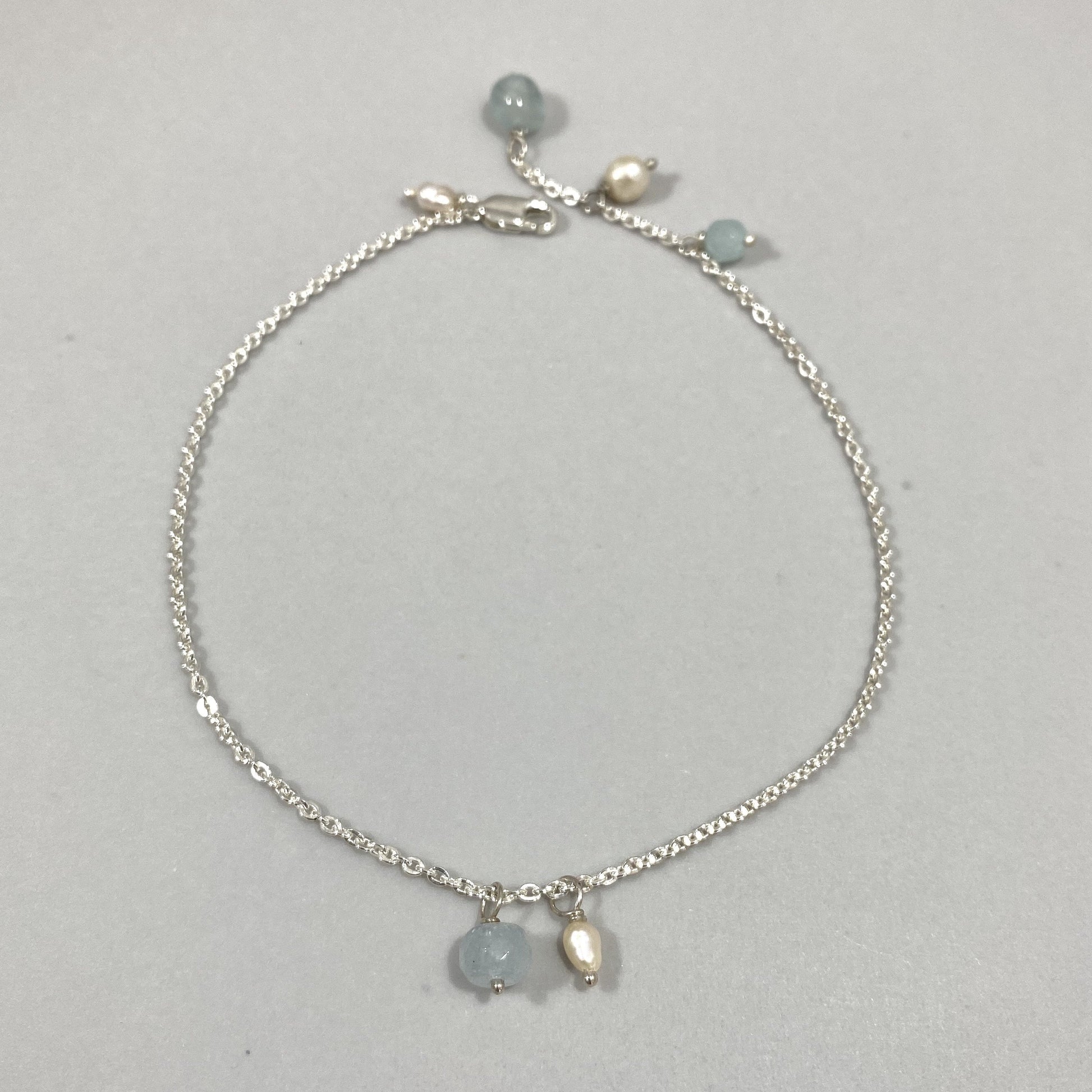 Tornozeleira corrente cartier em prata 925 polida (clara), com pedras água-marinha e pérolas. Comprimento: regulagem entre 23cm e 25,5cm. Para outras medidas entre em contato. Embalagem de algodão Santacosta. Esta é uma joia de prata 925 produzida com uma liga conhecida internacionalmente com STERLING SILVER – 925, o que significa que ela é constituída de 92,5% de prata pura, garantindo a qualidade do material utilizado. Por se tratar de pedras naturais, podem apresentar variações na coloração.